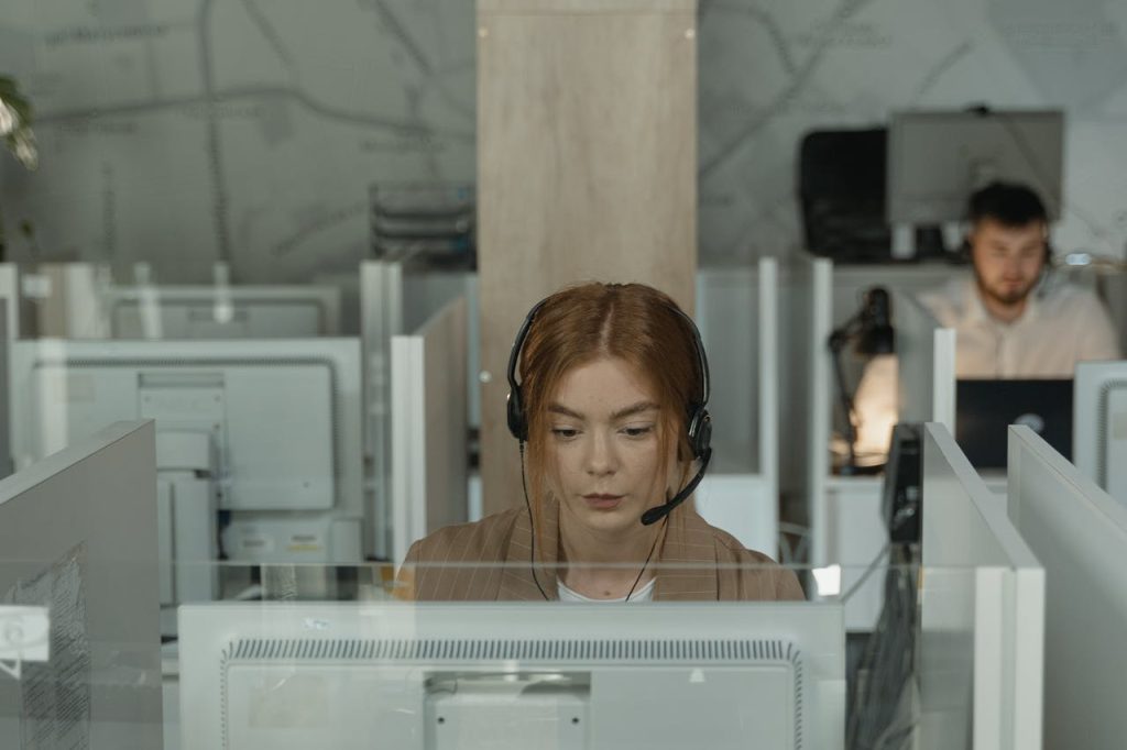 Focused call center agent wearing headset working in cubicle office space